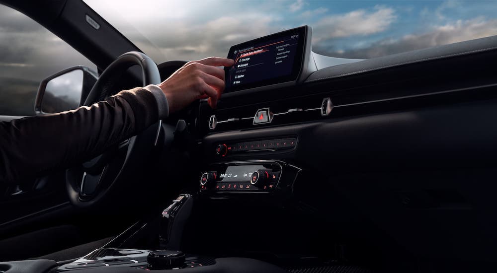 A hand is shown using the infotainment screen in a 2020 Toyota GR Supra.