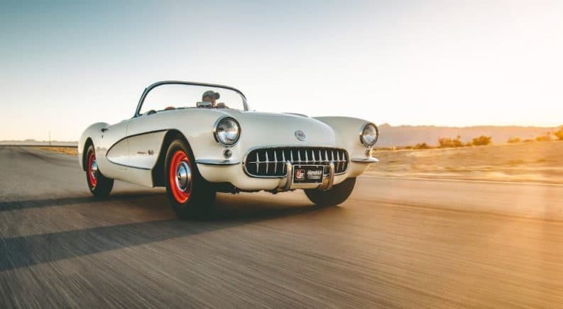 A white 1957 Chevrolet Corvette is driving down the road after being purchased from Tri-Five cars and trucks.
