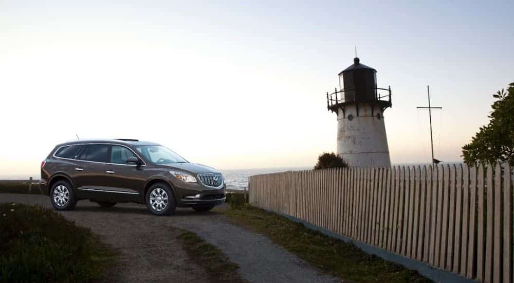 A grey 2013 used Buick Enclave is parked with a lighthouse in the background.