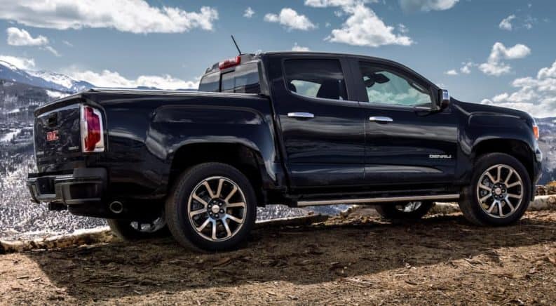 A black 2020 GMC Canyon Denali is parked in front of mountains after winning the 2020 GMC Canyon vs 2020 Nissan Frontier comparison.