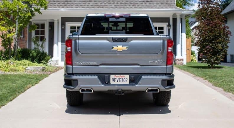 A grey 2021 Chevy Silverado 1500 is shown from the rear in front of a house.