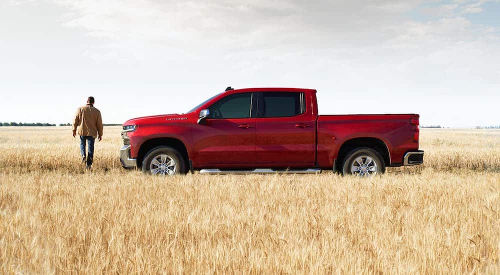 A red 2021 Chevy Silverado 1500 Trailboss LT is parked in the middle of a field.