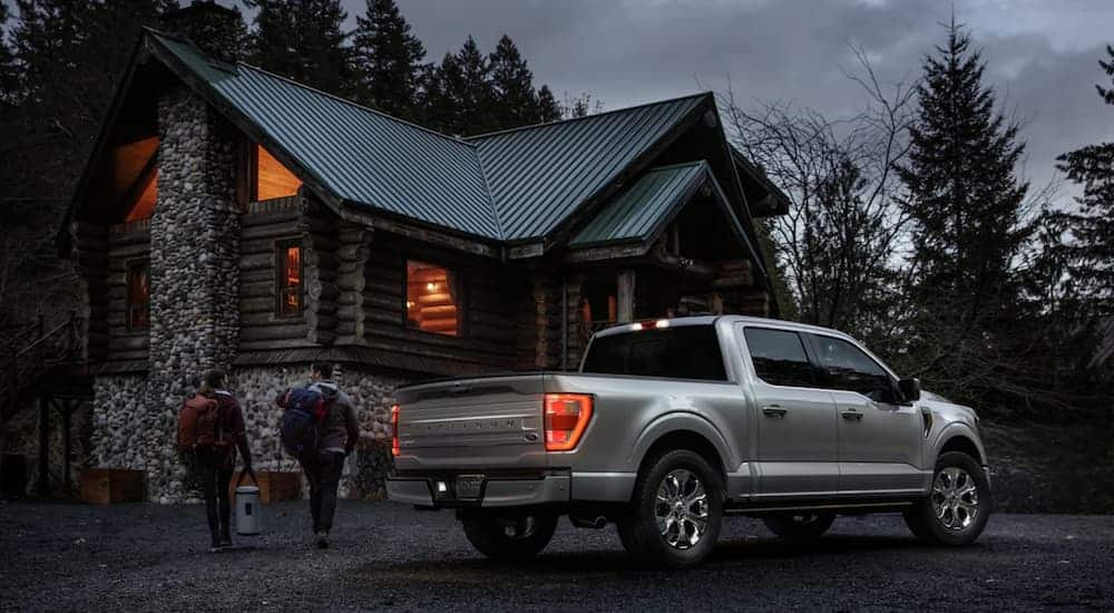 A silver 2021 Ford F-150 Platinum is parked outside a cabin.