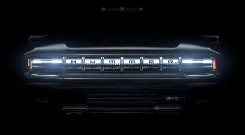 The front grill of a 2021 GMC Hummer EV is only showing the front grill and the rest is veiled in darkness.