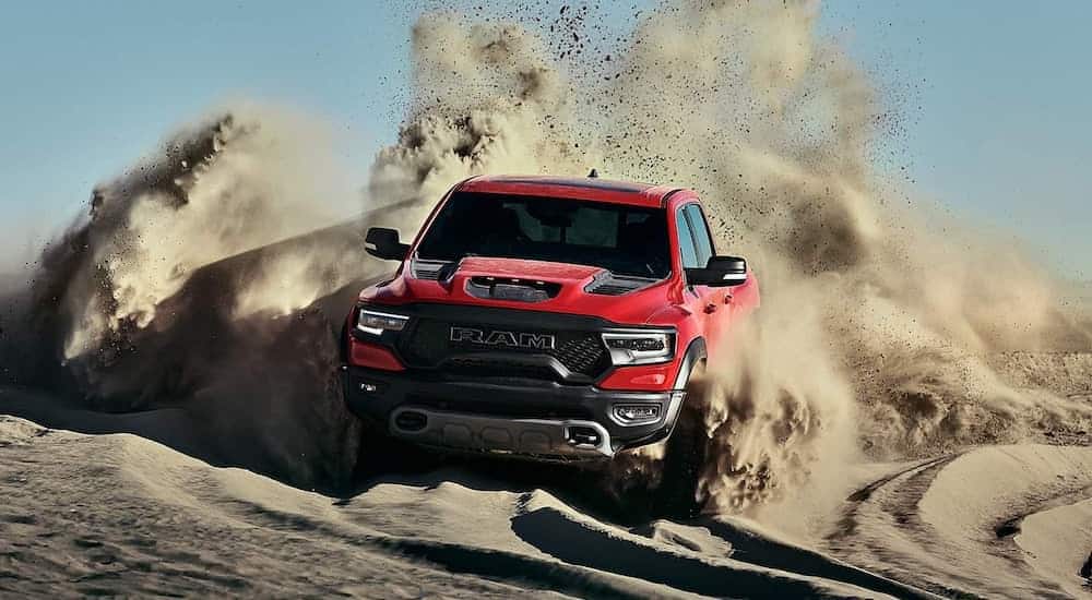 A red 2021 Ram 1500 TRX is off roading in the desert kicking up dust in its wake.
