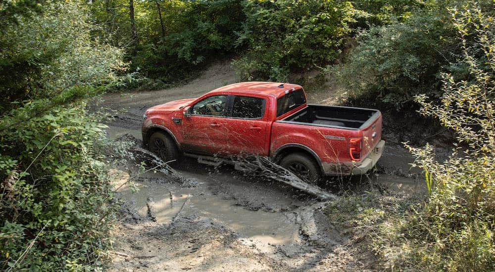 A red 2021 Ford Ranger Tremor is off-roading on a muddy trail.