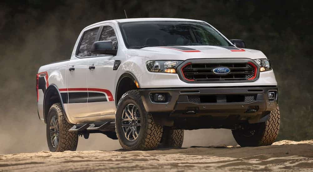 A Ford truck with a new package, a white 2021 Ford Ranger Tremor, is driving off-road on dirt.