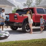 A red and black 2019 used Ram 1500 for sale is shown being loaded with beach gear while attached to a boat trailer.