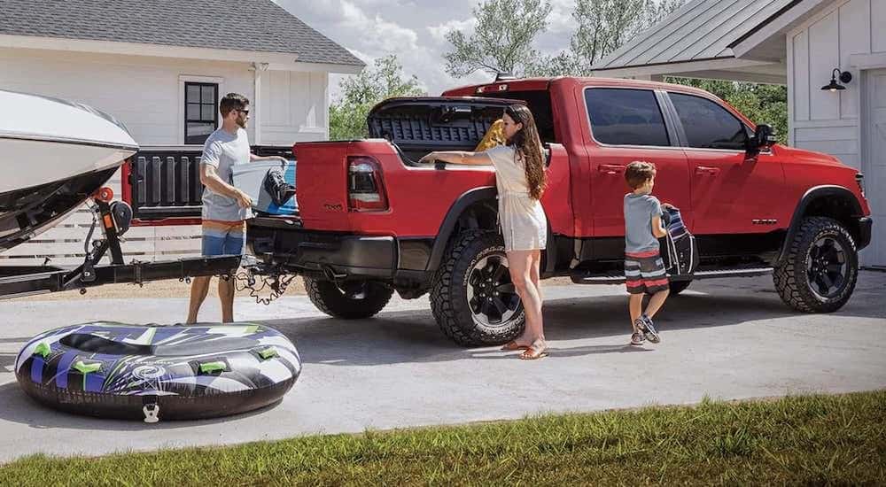 A red and black 2019 used Ram 1500 is being loaded with beach gear while attached to a boat trailer.