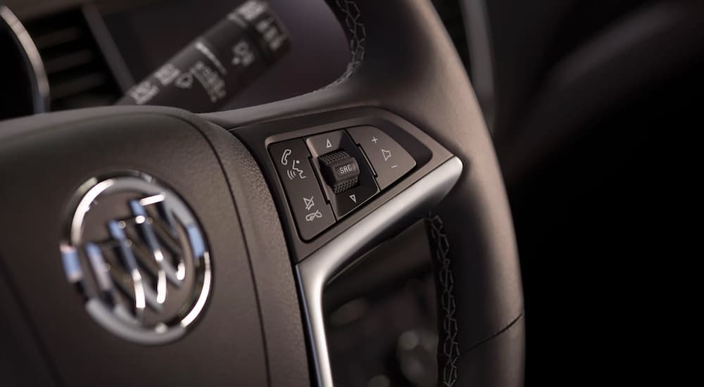A close up of the silver and black interior and steering wheel controls are shown on a 2021 Buick Encore.