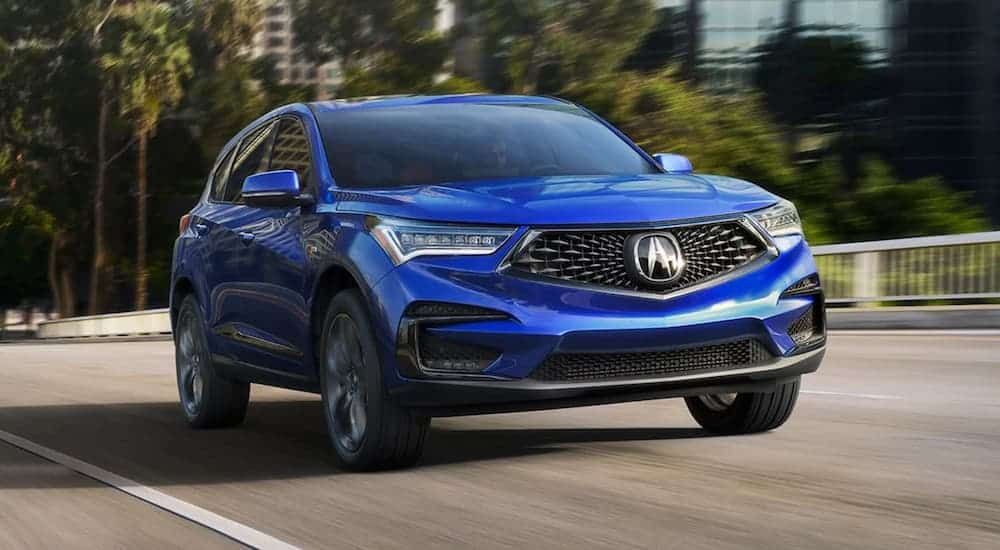 A blue 2021 Acura RDX is driving down a blurred road.