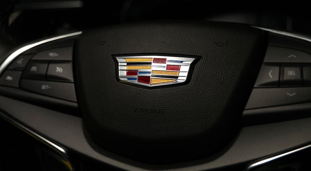A close up is shown of the black steering wheel and Cadillac emblem on a 2021 Cadillac XT5.