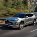 A silver 2021 Chevy Blazer is driving down the highway past a river.