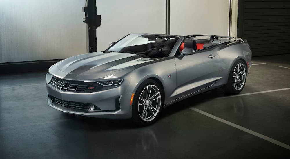 A silver 2021 Chevy Camaro convertible is parked in a garage after winning the 2021 Chevy Camaro vs 2021 Ford Mustang comparison.