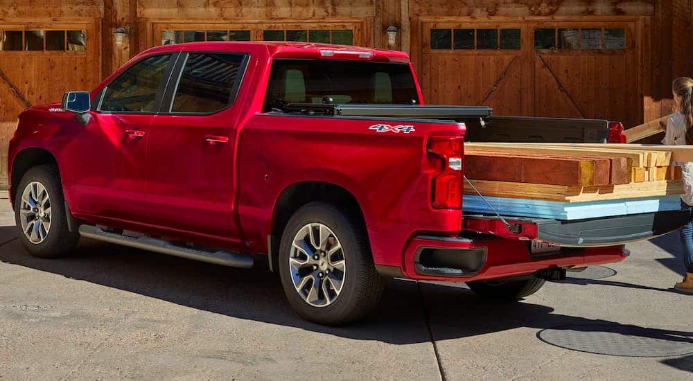 A red 2021 Chevy Silverado 1500 is parked on a construction site with lumber in the bed.