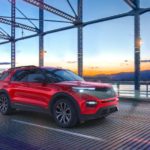 A red 2021 Ford Explorer ST is driving down a bridge at sunset.