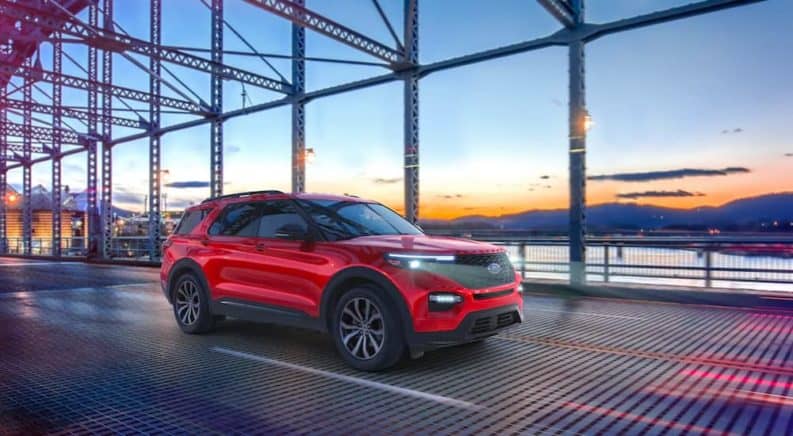 A red 2021 Ford Explorer ST is driving down a bridge at sunset.