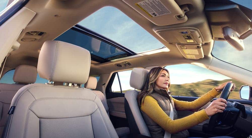 A woman is shown from a low angle driving a 2021 Ford Explorer.