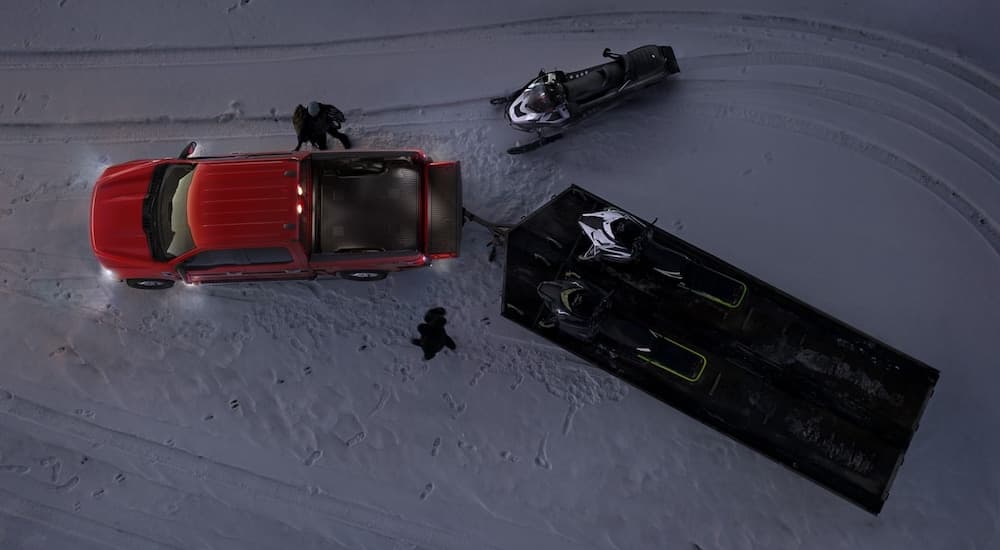 A red 2021 Ford F-150 is shown from above parked in the snow with a snowmobile trailer after winning the 2021 Ford F-150 vs 2021 Chevy Silverado 1500 comparison.