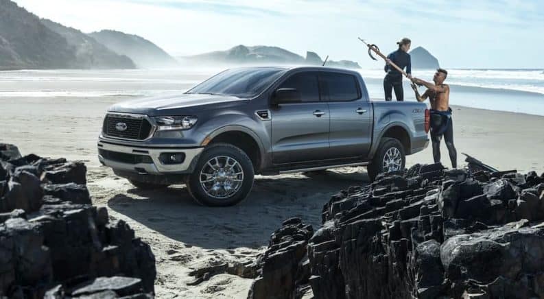 A silver 2021 Ford Ranger XLT is parked on the beach with people loading fishing gear in to the bed.