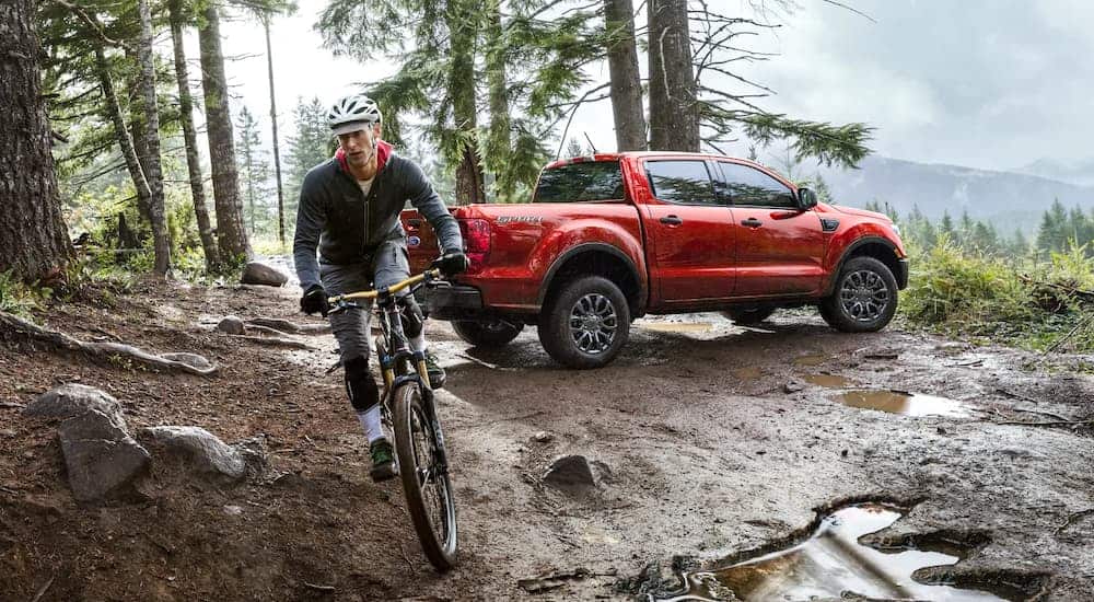 A red 2021 Ford Ranger is parked in the woods with a person biking away from it.