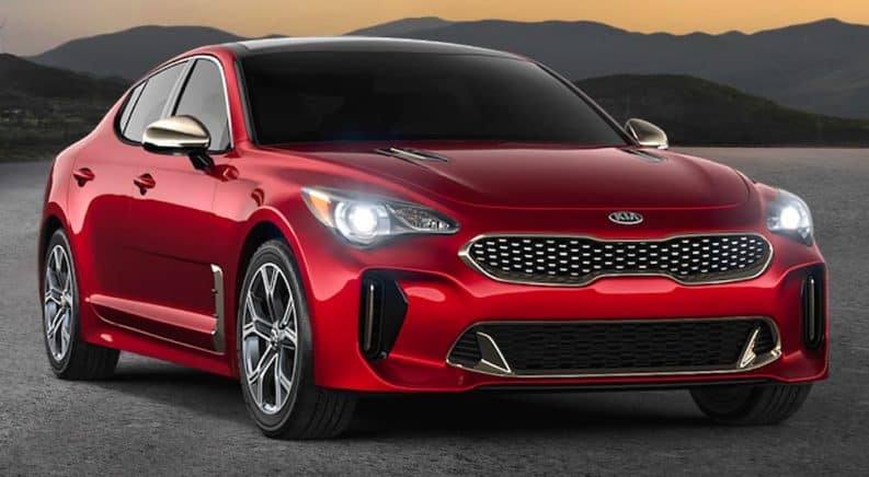 A red 2021 Kia Stinger is parked at sunset shown from the front angled right.