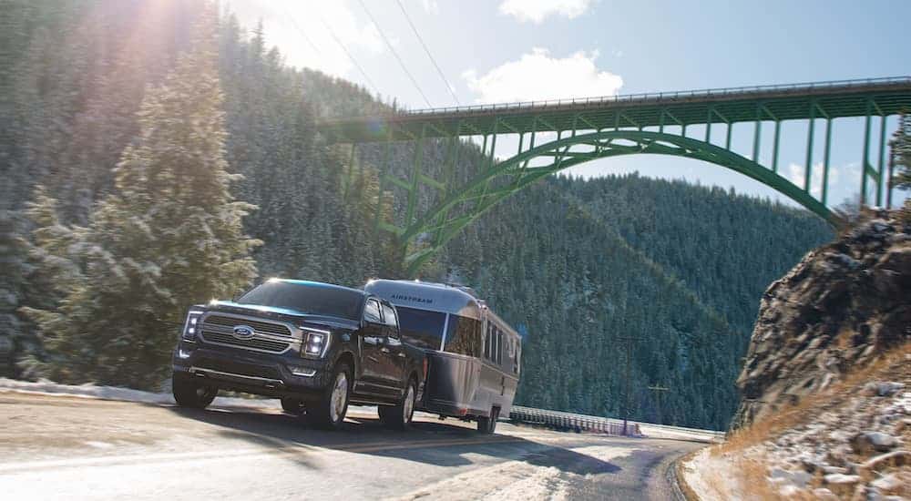 A black 2020 used Ford F-150 Limited is towing an airstream trailer under a green bridge.