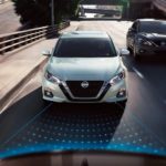 A white 2019 used Nissan Altima is shown from the front driving down the highway.