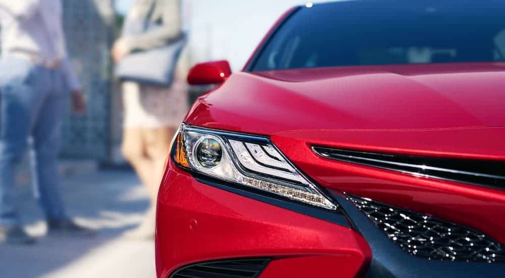A close up is shown of the passenger headlight on a red 2019 Toyota Camry.