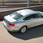 A silver 2020 Chevy Impala is shown from a high angle driving on a highway.