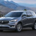 A grey 2021 Buick Enclave Avenir is parked at a pull off overlooking mountains.