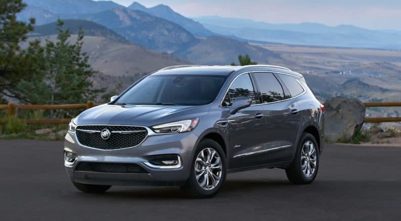 A grey 2021 Buick Enclave Avenir is parked at a pull off overlooking mountains.