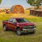 A red 2021 Chevy Silverado 1500 is parked in front of wooden barns.
