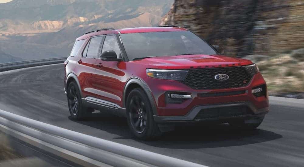 A red 2021 Ford Explorer Hybrid is driving around a winding mountain road.
