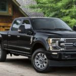 A black 2021 Ford Super Duty Limited F-250 is parked in front of a cabin.