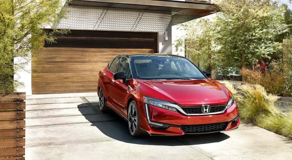 A popular 2021 Honda Hybrid, a 2021 Honda Clarity Fuel Cell, is parked in front of a wooden garage.