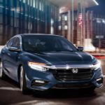 A blue 2021 Honda Insight is driving through the city at night.