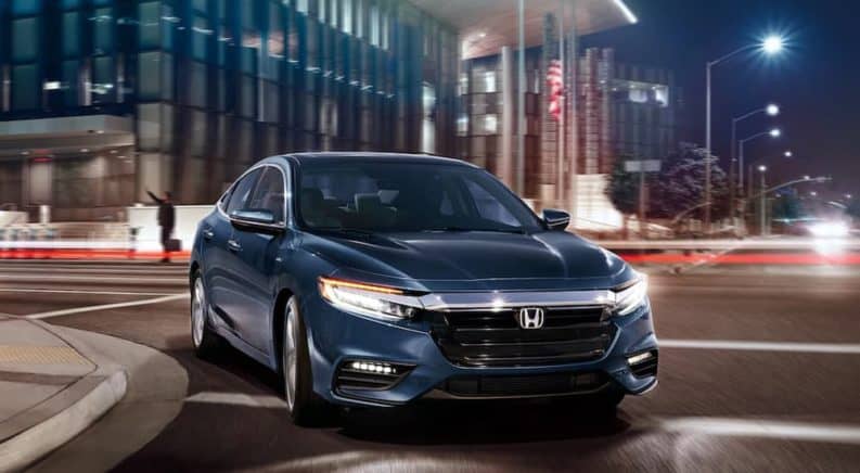 A blue 2021 Honda Insight is driving through the city at night.