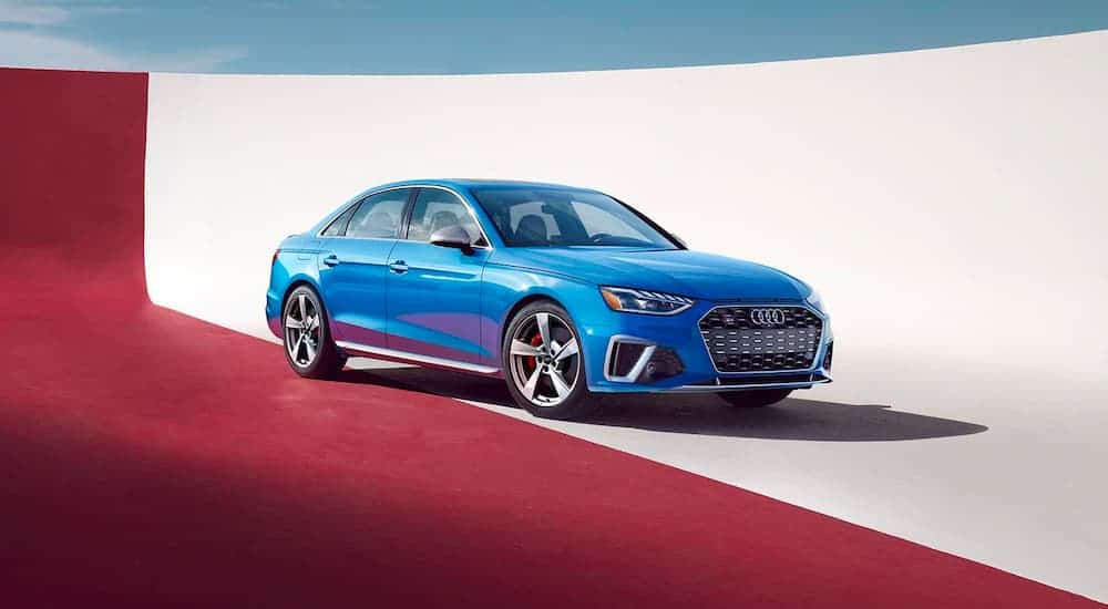 A blue 2021 Audi S4 is shown angled left, parked against a divided red and white background.