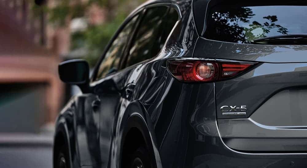 A dark grey 2021 Mazda CX-5 is shown from the rear angled left.