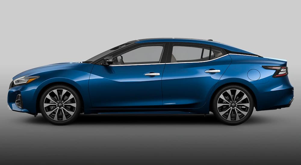 A blue 2021 Nissan Maxima is shown from the side against a grey background.