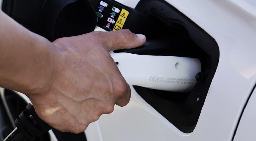 A hand is shown plugging in a 2022 Jeep Grand Cherokee 4xe to charge.