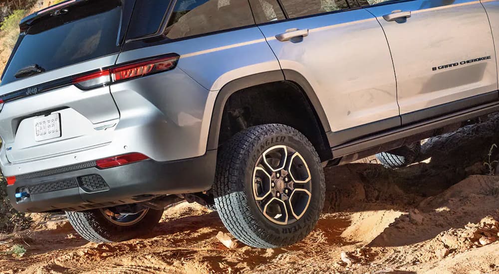 A silver 2022 Jeep Grand Cherokee 4xe off-roading in the desert.
