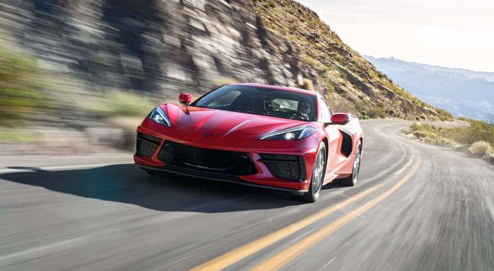 A red 2020 Chevy Corvette Stingray is driving on a rocky highway.