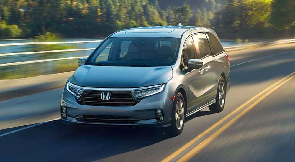 A gray 2020 Honda Odyssey is driving on a highway past a river after leaving an Albany used car dealership.