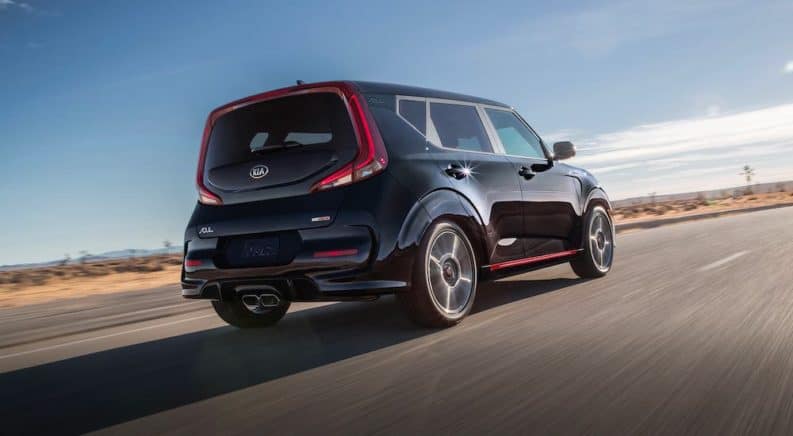 A black 2020 Kia Soul is shown from the rear driving on an empty highway.