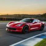 A red 2017 Chevy Corvette Grand Sport is shown driving around a race track on a sunny day.