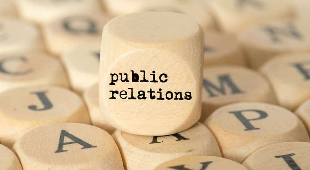 A square wooden block that says public relations is on top of many blocks with letters on them.