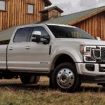 A popular Ford Diesel truck, a silver 2021 Ford F-350 Super Duty, is parked in front of a barn.