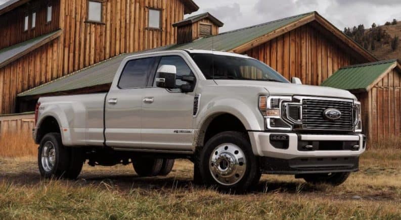 A popular Ford Diesel truck, a silver 2021 Ford F-350 Super Duty, is parked in front of a barn.